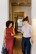 © BONNINSTUDIO/Stocksy - Businesswomen smiling, walking through an entrance
