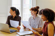 © BONNINSTUDIO/Stocksy - Female professionals collaborating and smiling during office meeting