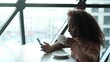 © ekaterinabyuksel - Cute African American woman drinking coffee or tea and using mobile phone in cafe