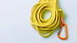 © A2Z AI  - Bright coiled yellow rope and orange safety clip on a clean white surface with copy space, ready for adventurous outdoor activities or utility tasks