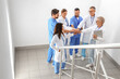 © Pixel-Shot - Team of doctors putting hands together on stairs in clinic