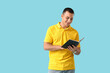 © Pixel-Shot - Handsome young happy man reading book on blue background