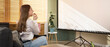 © Pixel-Shot - Young woman eating popcorn and watching a movie on a projector screen at home, entertainment and leisure activity