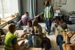 © pressmaster - Wide shot of diverse families sheltering in emergency relief center, receiving water and registration support from aid workers. Ideal for disaster response, humanitarian outreach campaigns