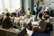 © pressmaster - Wide shot of diverse adults and child resting on cots while aid workers distributing blankets and support in shelter, conveying crisis response. Ideal for humanitarian outreach campaigns