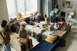 © pressmaster - Wide angle view of diverse adults receiving shelter support, resting on cots, consulting volunteer staff in temporary housing center. Ideal for homelessness aid, crisis response campaigns