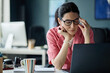 © Seventyfour - Middle aged Caucasian businesswoman rubbing eyes while working on laptop at desk, showing digital fatigue and stress. Useful for workplace burnout, remote work, wellness campaigns