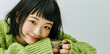 © Surachetsh - A joyful young Asian woman lounges comfortably on a cozy morning, smiling as she sips a warm cup of coffee or tea and lets herself drift into a daydream.