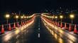 © Jiraporn - A reflective road at night lined with traffic cones and illuminated by long rows of bright lights.