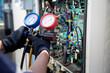 © kunakorn - Air conditioning, HVAC service technician using gauges to check refrigerant and add refrigerant,Air Conditioning Repair, repairman on the floor fixing air conditioning system.
