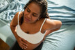 © Davor - Pregnant woman with back pain sitting on bed at home