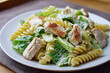 © Magryt - Grilled chicken Caesar pasta salad on a white plate, shot close-up. Fresh romaine, creamy dressing, comfort food, lunch and dinner, Italian-inspired and restaurant-style.