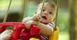 © Marco - Adorable baby infant on playground swing happy