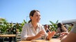 © INSPIRIA.K - Happy woman wearing hearing aid talking with friend at outdoor cafe. Healthcare technology for deaf person.