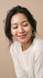 © mubashar - Radiant Asian woman with glowing skin and closed eyes, serene female portrait for skincare and wellness, natural beauty in soft beige studio light