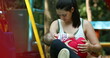 © Marco - Casual candid mother breastfeeding baby son outside at park
