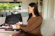 © Home-stock - Expectant mother carefully packing small baby shoes into open suitcase with infant clothing, getting ready for motherhood