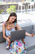 © ADDICTIVE STOCK - Mother and son using laptop and smartphone on patio sofa