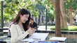 © blueringmedia - Young Thai University Student Using Smartphone While Studying Outdoors in Bangkok