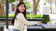 © blueringmedia - Smiling Young Thai Student Using Laptop at Outdoor University Campus Table