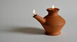 © Pete - Antique terracotta oil lamp with two burning wicks. Simple vase shape sits on white surface casting a minimal shadow. Warm, rustic glow illuminates dark space.