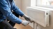 © Hasniah B - Radiator Repair and Heating System Maintenance by Technician Adjusting Valve for Efficient Home Climate Control