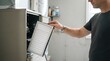 © SimpleDesignStudio - Adult caucasian man changing the air filter in a residential furnace in a basement