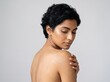 © Max_T - Portrait of a young woman with short dark hair looking down at her shoulder, natural makeup, glowing skin, studio shot against a neutral grey background