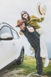 © Evaldas Mikoliunas/imageBROKER - Portrait Happy couple Man with woman having fun piggyback next to white car on coastal cliff. Vast blue ocean and mountain horizon create romantic, joyful travel mood. Summer holiday adventure vibes