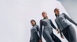 © Przemek - Three fit women in stylish grey sportswear standing confidently against a bright white architectural wall in an urban outdoor setting