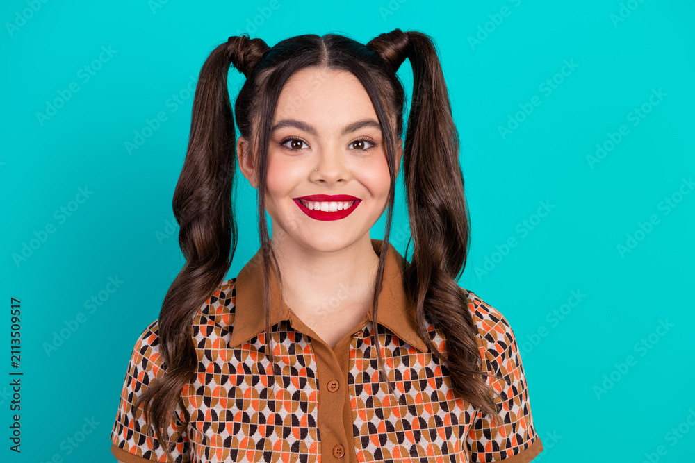 Glamorous young girl with pigtails smiles against teal background ...