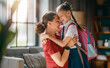 © Konstantin Yuganov - Happy Mother Hugging Daughter in School Uniform at Home Before School Day