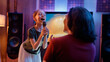 © Konstantin Yuganov - Joyful Child Singing Karaoke at Home with Family in Cozy Living room