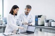 © saranya - Analytical chemistry laboratory with scientists using laptop and smartphone for advanced scientific research.
