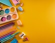 © April - school stationery in pastel colors arranged on the right side of a yellow background with large empty copy space on the left