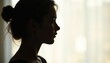 © Nataly - Silhouette of woman with bun hairstyle in profile against soft background light. Woman's silhouette captures calm mood in gentle light. Concept portrait photography for emotional expression.