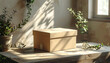 © fitri - Cardboard box on a wooden table, bathed in sunlight, with green plants and soft shadows, evoking a natural and calm atmosphere.