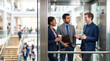© Taras Roshchuk - Three professionals stand in an elevator in a busy office building. They engage in conversation while one holds a coffee cup. Colleagues in the office are visible in the background