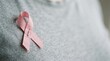 © velikiyzayats - Pink breast cancer awareness ribbon pinned on a grey shirt representing hope and support for women health medical charity campaign
