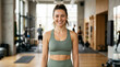 © Lina - Smiling young woman in green sportswear standing in a gym. Confident female fitness portrait. Body acceptance and healthy lifestyle concept