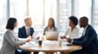 © CuteBee - Out of focus professional business team having a meeting around round wooden table in bright modern office with large panoramic windows overlooking city skyline during sunny day