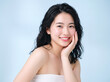 © kitthanes  - Generative AI, A beautiful young Asian woman with clean, fresh skin against a blue background. Skincare, facial treatment, cosmetology, beauty, and spa. An elegant portrait of an Asian woman,