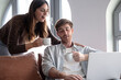 © luciano - Couple collaborating online, drinking coffee and working together from home on laptop, creating a shared experience with digital content at apartment