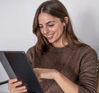 © luciano - Smiling young adult woman using a digital tablet for online browsing, communications, and learning while enjoying a relaxed moment at home