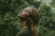 © TENphoto - Woman with closed eyes in green forest setting