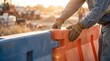 © 123sasha - Worker sets up a barrier on a construction site during sunset to improve safety and control traffic flow in the area
