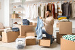 © Pixel-Shot - Young man with wardrobe boxes putting shirt on hanger in dressing room