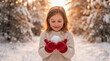 © ViskBx - A happy young girl holding a snowball in her red mittens in a snowy winter forest during sunset