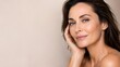 © Andefastudio - Beautiful Mature Woman Touching Her Face and Smiling Against a Beige Background