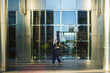 © pablo - Woman walking confidently outside a contemporary office building, reflecting city life